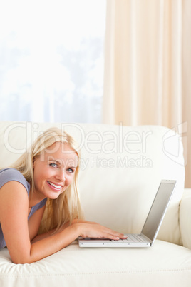 Woman lying on a couch with a laptop