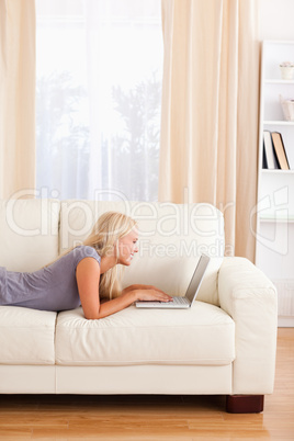 Portrait of a woman lying on a couch using a notebook