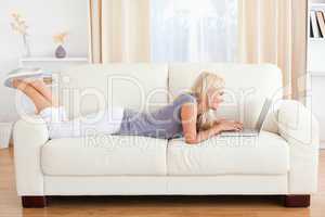 Woman lying on a sofa using a laptop