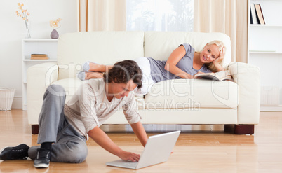 Man using a laptop while his girlfriend is holding a book