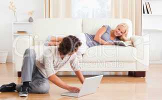 Man with a laptop while his girlfriend is holding a book