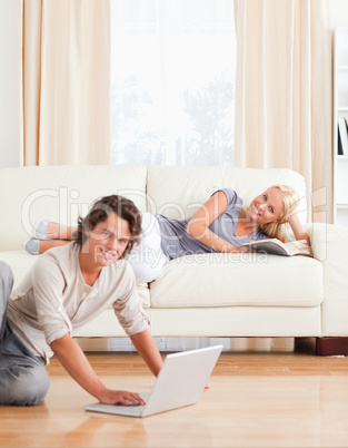 Portrait of a man with a laptop while his girlfriend is with a b