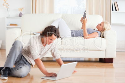Man using a laptop while his wife is reading a book