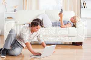 Man using a laptop while his wife is reading a book