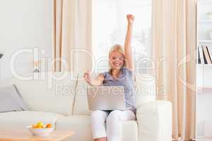 Woman raising her arms while using a laptop