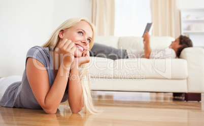 Woman lying on the floor while her boyfriend is reading a book