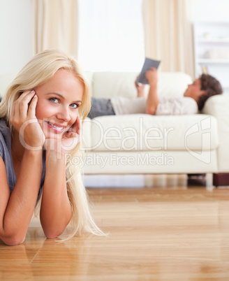 Portrait of a woman lying on the floor while her husband is read