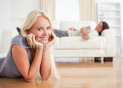 Woman lying on the floor while her fiance is with a book