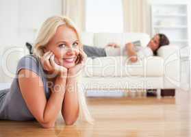 Woman lying on the floor while her fiance is with a book