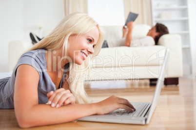 Woman using a laptop while her husband is reading