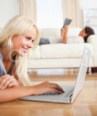 Portrait of a woman using a laptop while her husband is reading