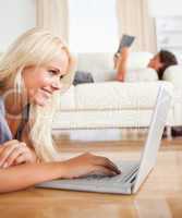 Portrait of a woman using a laptop while her husband is reading