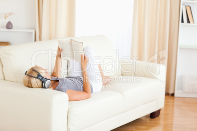 Woman enjoying some music while reading a book