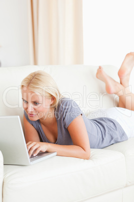 Portrait of a lying woman using a laptop