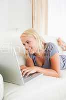 Portrait of a lying blonde woman using a notebook