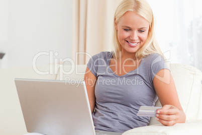 Woman looking at her credit card while holding her laptop