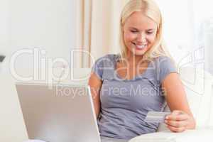 Woman looking at her credit card while holding her laptop