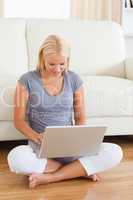 Woman using a laptop while sitting on the floor