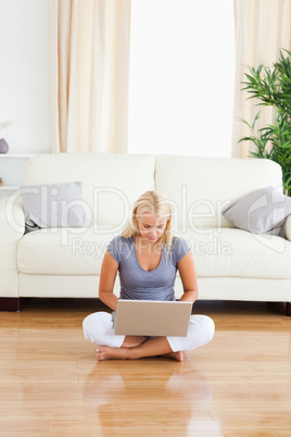 Portrait of a woman using a laptop while sitting on the floor