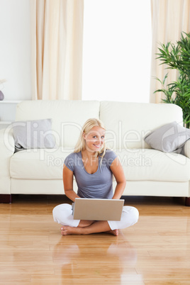 Portrait of a woman with a laptop while sitting on the floor