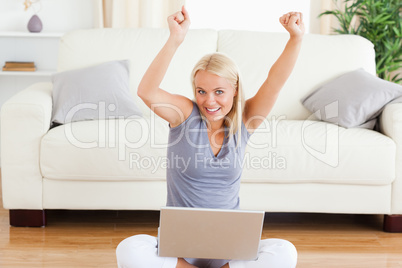 Cheerful woman using a notebook while sitting on the floor
