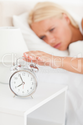 Portrait of a blonde woman awaken by an alarmclock