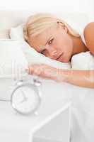 Portrait of a cute woman awaken by an alarmclock