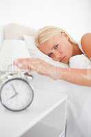 Portrait of a tired woman awaken by an alarmclock