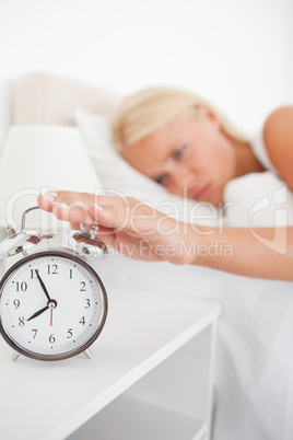 Portrait of an unhappy woman switching off her alarmclock