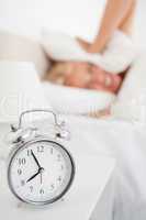 Portrait of a woman hidding her head in a pillow while the alarm