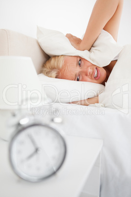 Portrait of a tired woman hidding her head in a pillow while the