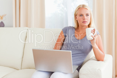 Woman having a tea while holding a laptop