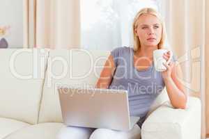 Woman having a tea while holding a laptop