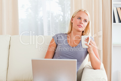 Woman having a coffee while holding a laptop