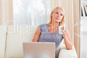 Woman having a coffee while holding a laptop