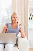 Portrait of a woman having a coffee while holding a laptop