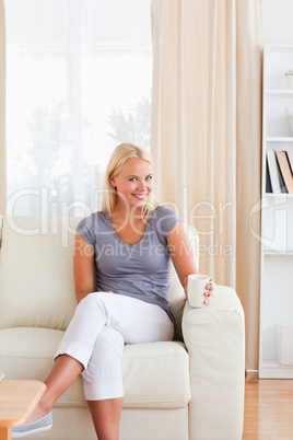 Portrait of a woman sitting on a sofa with a cup of tea