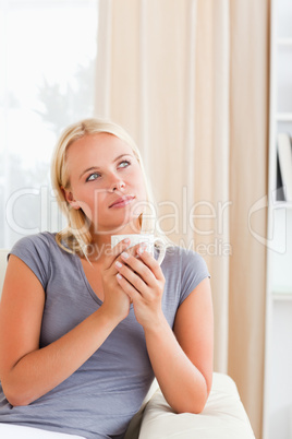 Portrait of a woman sitting on a sofa with a cup of coffee