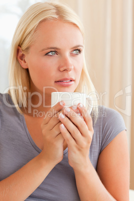 Portrait of a calm woman sitting on a couch with a cup of coffee