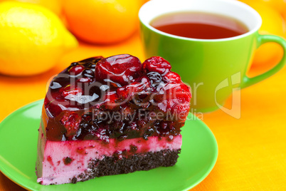 beautiful cake with berries on a plate and a cup of tea on the o