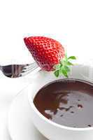 melted chocolate in a cup, fork and strawberries isolated on whi