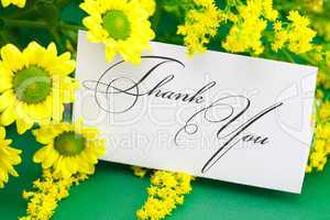yellow daisy and card signed thank you on green background