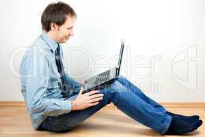 young man using laptop sitting on the floor in the room