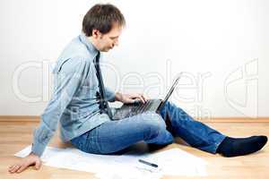 young man using laptop sitting on the floor in the room