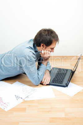 young man using laptop  lying on the floor in the room