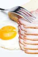 bacon with  fried  eggs on a plate, fork and bread isolated on w