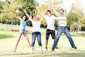 Family jumping high in the air on a green meadow