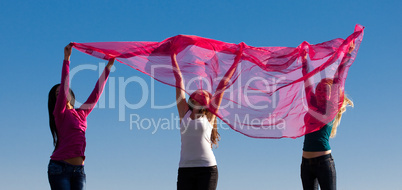 three young beautiful woman jumping with tissue into the field a