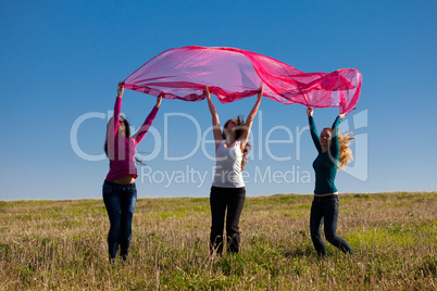 three young beautiful woman jumping with tissue into the field a