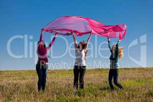 three young beautiful woman jumping with tissue into the field a